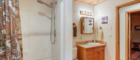 Un baño con ducha, inodoro, lavamanos y armarios de madera.