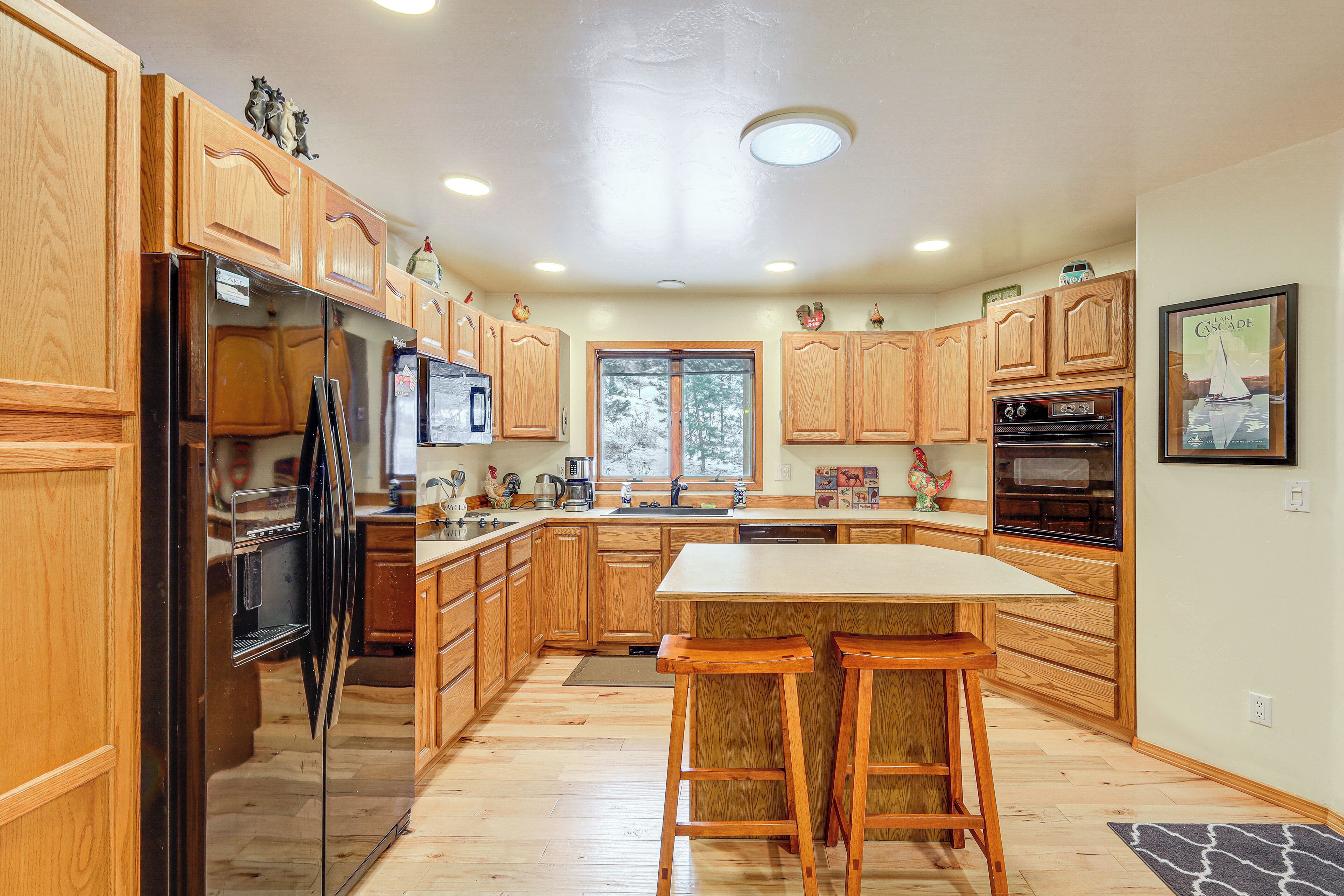 A kitchen with wooden cabinets, a refrigerator, a microwave, a sink, and a large island with bar stools.