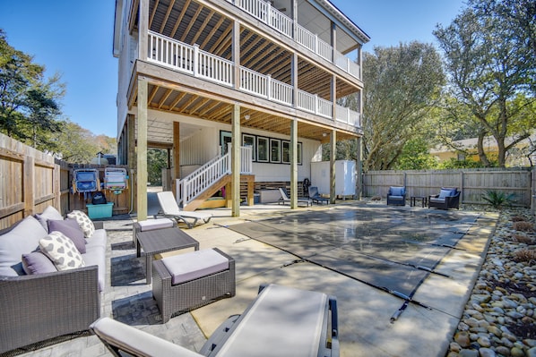 A two-story house with a covered patio area, outdoor furniture, and a wooden deck.