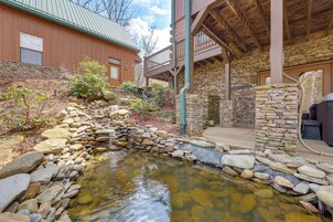 Un bâtiment en pierre doté d’une terrasse en bois et traversé par un petit ruisseau.