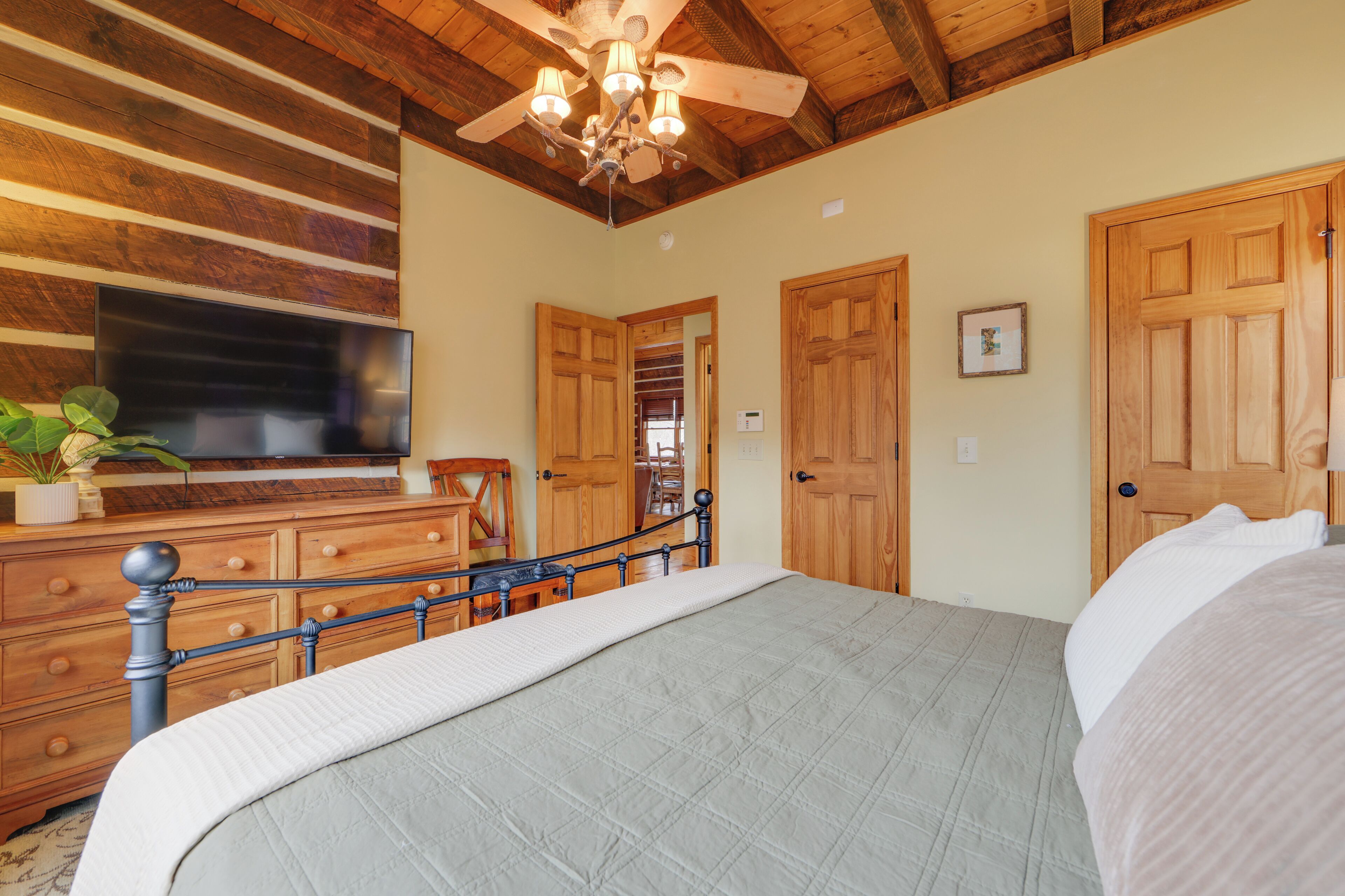 Ein Schlafzimmer mit einem Bett, einem Holzschrank, einem Fernseher und einem Deckenventilator.