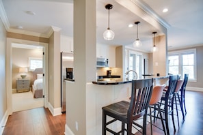 A modern kitchen with a central island, pendant lighting, and a dining area with bar stools.
