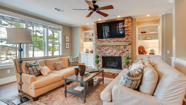 A living room with a stone fireplace, two sofas, a coffee table, and a ceiling fan. - Condo on Lake Oconee: Big Water Views (Greensboro)