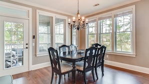 A dining room with a dark wooden table and chairs, a chandelier, and large windows with blinds. - Condo on Lake Oconee: Big Water Views (Greensboro)