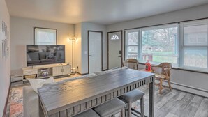 Ein modernes Wohnzimmer mit Flachbildfernseher, Esstisch und einer Couch.