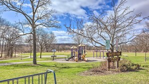 Ein Park mit einem Spielplatz, einem Schild mit der Aufschrift Baxter Park und einem gepflasterten Weg.