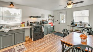 A modern kitchen with grey cabinets, a wooden dining table, and a ceiling fan. - Walk to Restaurants & Markets: Machias Home! (Machias)