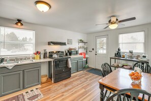 A modern kitchen with grey cabinets, a wooden dining table, and a ceiling fan. - Walk to Restaurants & Markets: Machias Home! (Machias)