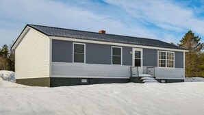 A single-story house with a dark roof and light siding, surrounded by snow. - Walk to Restaurants & Markets: Machias Home! (Machias)