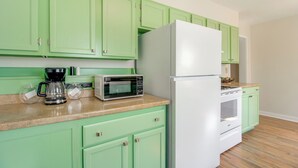 A kitchen with green cabinets, a white refrigerator, a microwave, and a coffee maker. - Lakes, Whiskey & More! Charming Home in Tullahoma (Tullahoma)