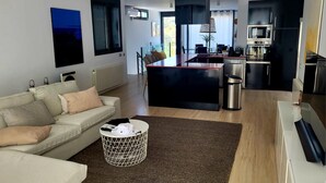 Una sala de estar moderna con un sofá, una mesa de centro y una zona de cocina con electrodomésticos.