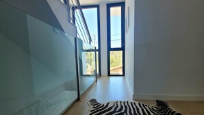 Un interior moderno con una pared de vidrio, una alfombra de estampado de cebra y vista a un área exterior a través de una puerta.