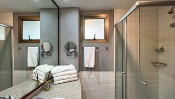 A bathroom with a sink, mirror, two towel racks, and a glass shower enclosure.