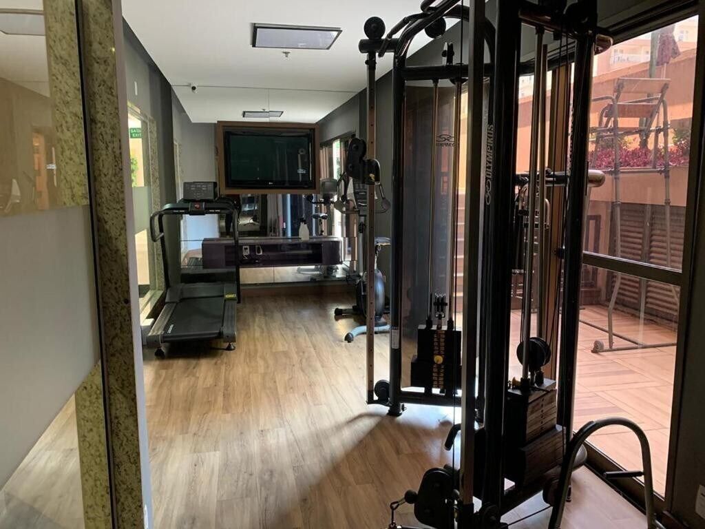 A gym with exercise equipment, a treadmill, and a television screen.