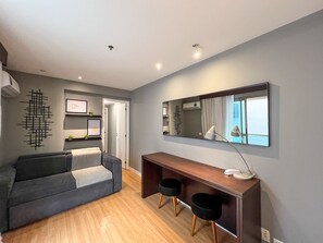 Un salon moderne avec un canapé gris, une console en bois, un grand miroir et un luminaire suspendu au plafond.
