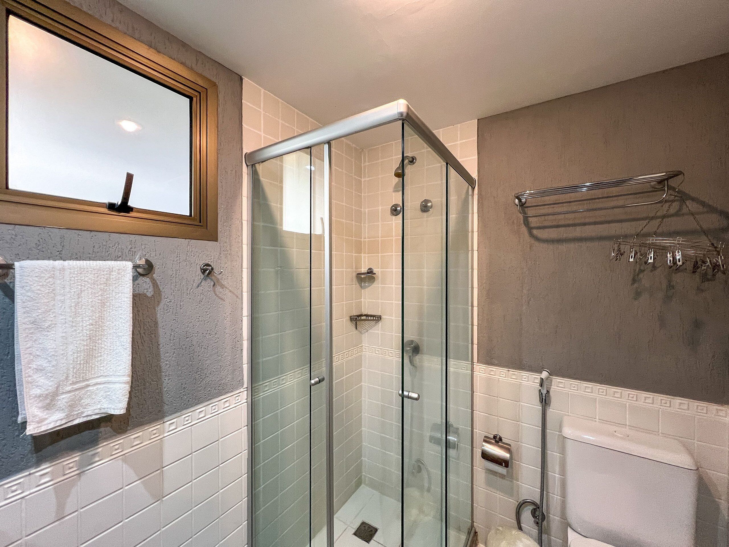 A bathroom with a glass shower enclosure, a towel rack, and a toilet.