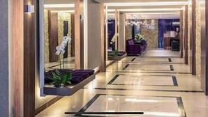 A modern hotel lobby with a reflective floor, wooden columns, and a central seating area with purple cushions. - Premium Copacabana - Rio de Janeiro (Rio de Janeiro)