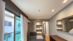 A modern hotel room with a sofa, a desk, a mirror, and a view through a large window. - Premium Copacabana - Rio de Janeiro (Rio de Janeiro)