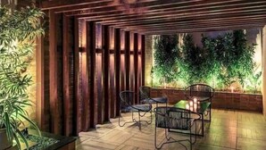 An outdoor patio area with wooden slatted ceiling, two chairs, a table, and a potted plant. - Premium Copacabana - Rio de Janeiro (Rio de Janeiro)