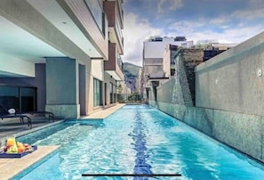 Une piscine offrant une vue dégagée et s’étendant sur une longue distance, entourée d’immeubles modernes.