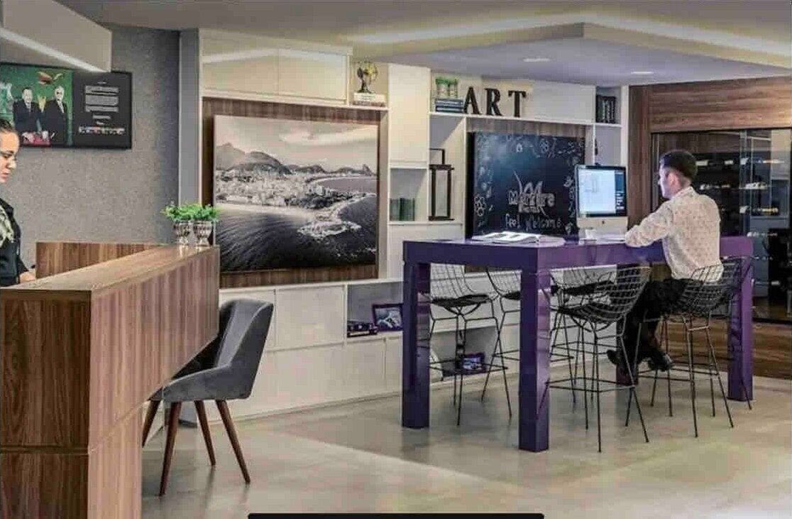 A modern reception area with a wooden desk, a computer, and a large framed picture on the wall.