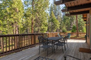 A wooden deck with a table and chairs, surrounded by a wooden railing, overlooking a forested area. - Mustang Sally- Free Lake Access! (Arnold)