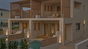Μια σύγχρονη διώροφη κατοικία με πισίνα, εξωτερικό χώρο καθιστικού και σκάλα που οδηγεί στον πάνω όροφο.