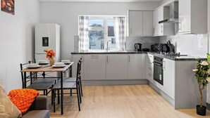 Una cocina moderna con armarios grises, horno empotrado y ventana con cortinas.