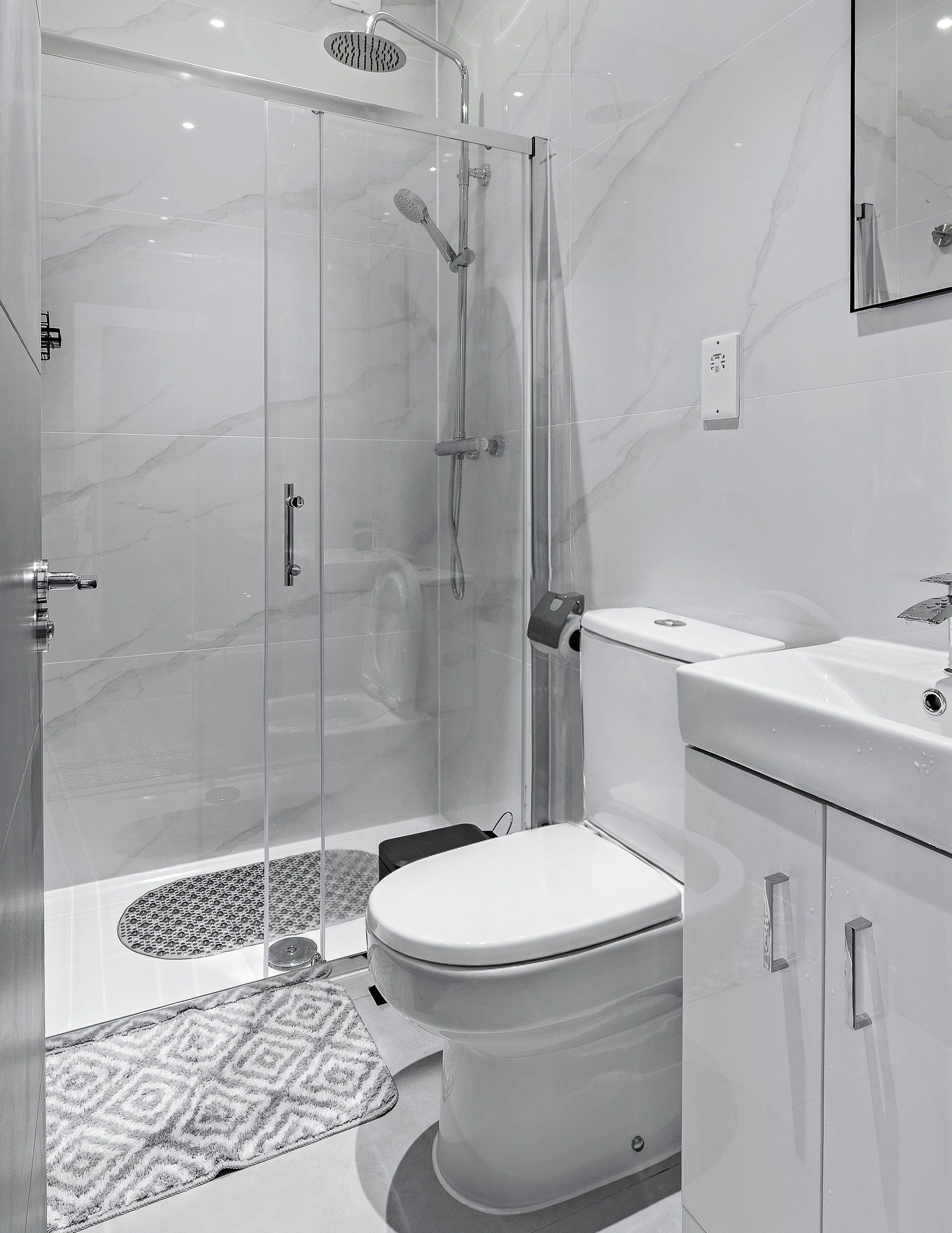 A modern bathroom with a glass-enclosed shower, a toilet, and a sink.