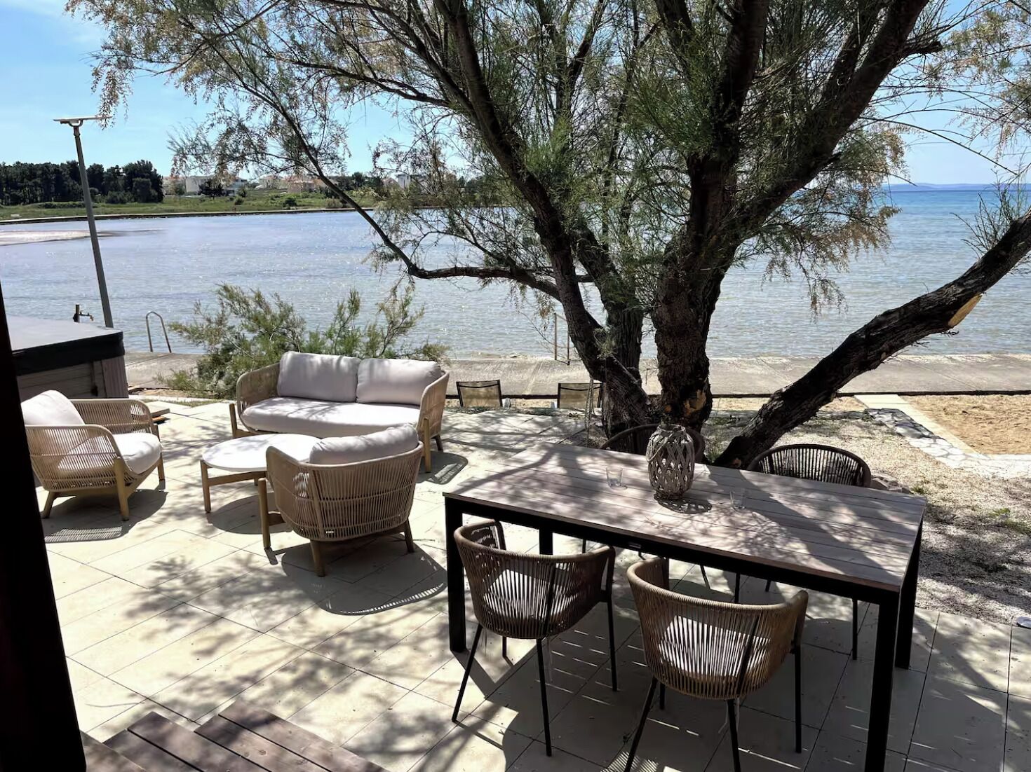 An outdoor seating area with wicker furniture, a table, and a view of the water.