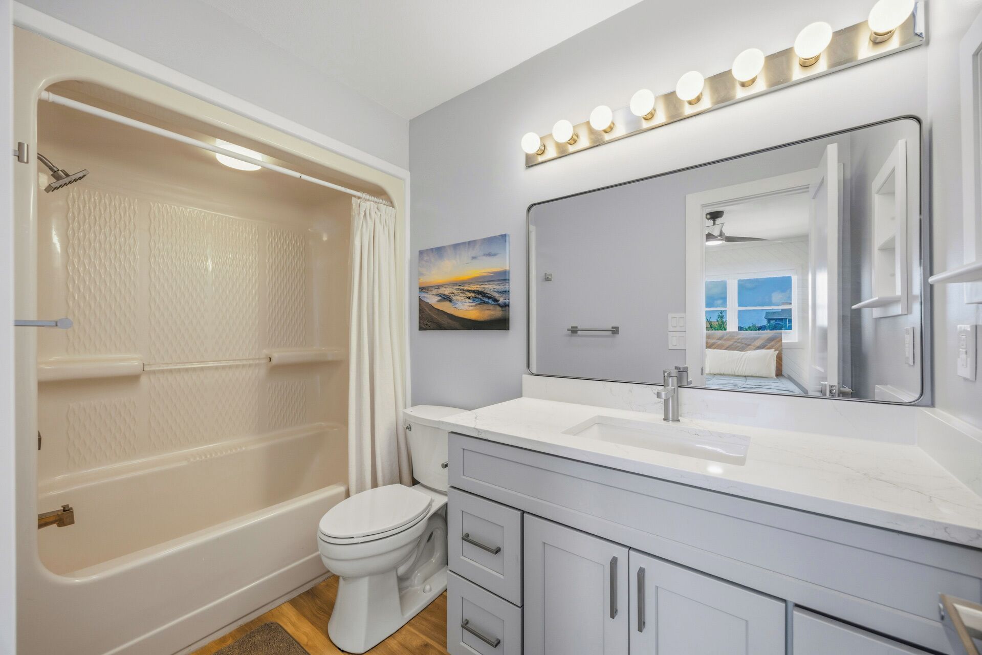 Une salle de bain équipée d’une baignoire, de toilettes, d’un meuble-lavabo avec un miroir et d’un rideau de douche.