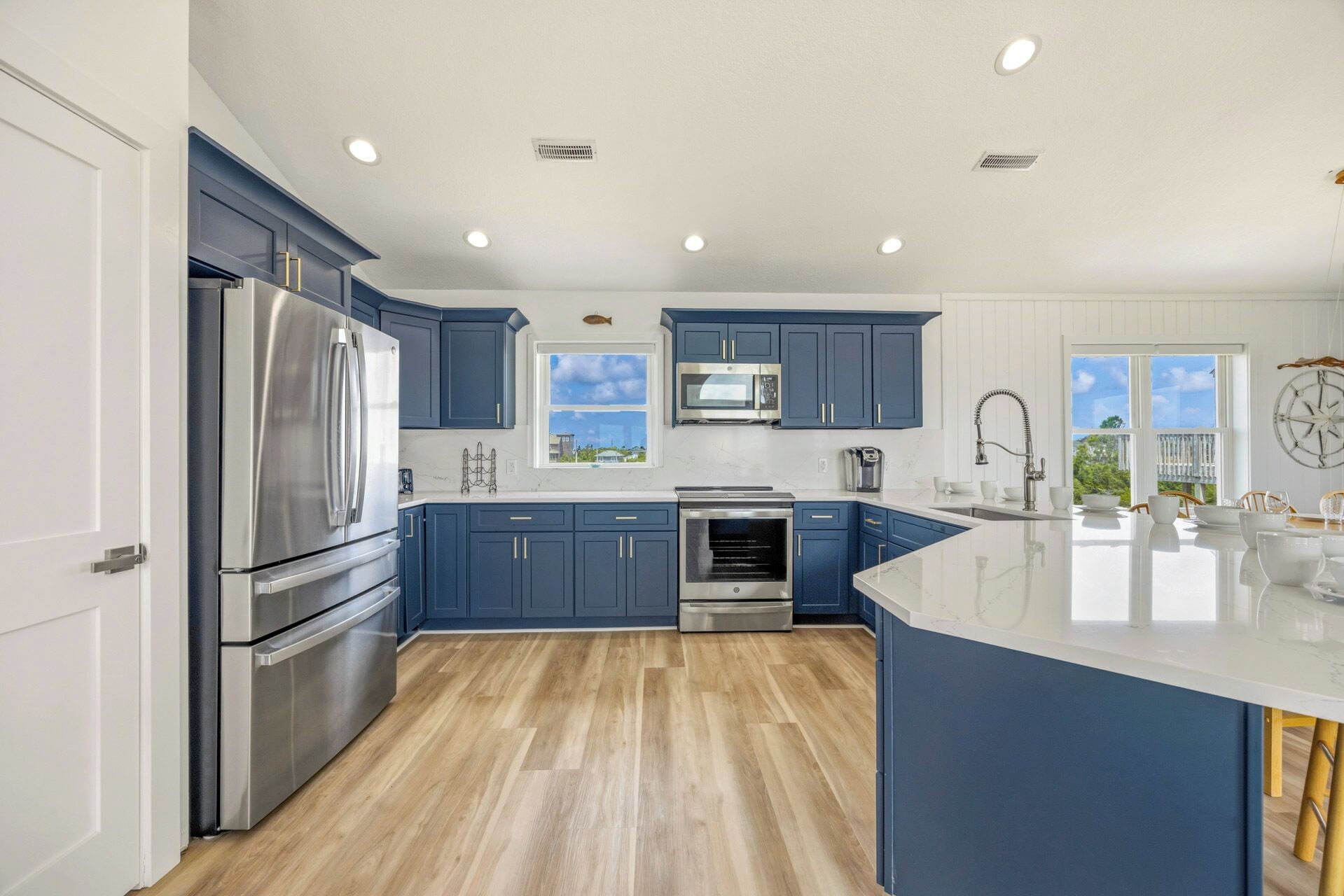 Een moderne keuken met donkerblauwe kastjes, roestvrijstalen apparatuur en een groot eiland.