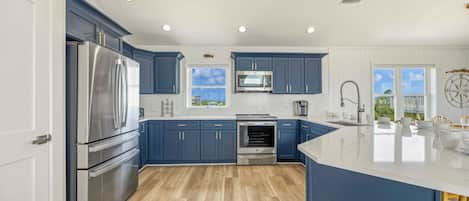 Een moderne keuken met donkerblauwe kastjes, roestvrijstalen apparatuur en een groot eiland.