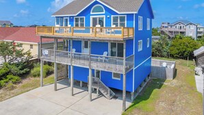 A two-story house with a balcony and a covered porch. - Brand New Semi-Oceanfront Waves Home with Private Pool, Hot Tub and Game Room (Waves)