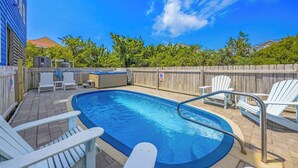 A rectangular swimming pool with a hot tub, surrounded by a wooden fence, and white deck chairs. - Brand New Semi-Oceanfront Waves Home with Private Pool, Hot Tub and Game Room (Waves)