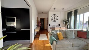 Ein modernes Wohnzimmer mit einer Couch, einem Essbereich und einer Küche mit Einbauofen und Mikrowelle.