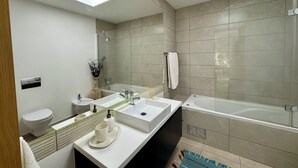 Ein modernes Badezimmer mit einer Badewanne, zwei Waschbecken, einer Toilette und einer Dusche.