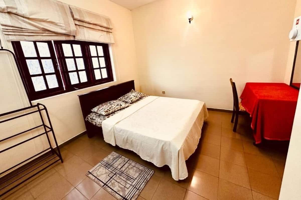 A small, neatly arranged bedroom with a bed, a small table, and a chair.