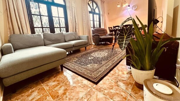 A living room with a sofa, a coffee table, a rug, a chair, and a TV.