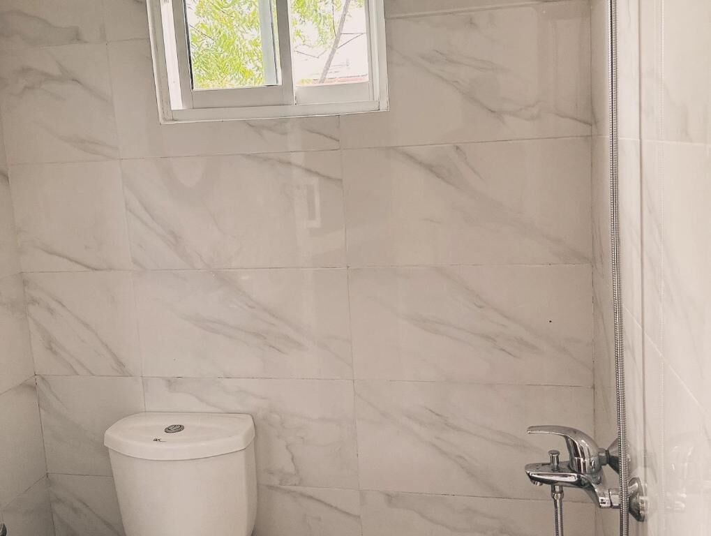 A bathroom with marble tiles, a toilet, and a shower.