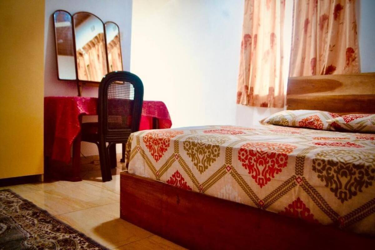 A bedroom with a bed, a chair, a desk, and a mirror.