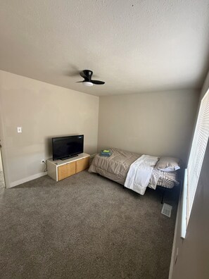 A small, sparsely furnished room with a single bed, a TV on a wooden stand, and a ceiling fan. - Delightful 5-bedroom house with AC for a relaxing stay (Toledo)