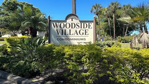 A sign for 'Woodside Village Condominiums' with a street lamp and lush greenery in the background. - 1/1 Beautiful Condo/15 mins to Clearwater beach/Peaceful neighborhood/With pools (Clearwater)