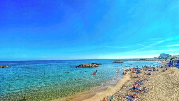 A beach with clear water, people swimming, and a hotel in the background. - House with pool 1 km from Sitges beach (Sant Pere de Ribes)