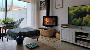 A cozy living room with a fireplace, a television, and a view of the outdoors. - House with pool 1 km from Sitges beach (Sant Pere de Ribes)