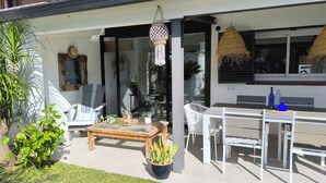 A covered outdoor area with a wooden table, white chairs, a hanging light fixture, and potted plants. - House with pool 1 km from Sitges beach (Sant Pere de Ribes)