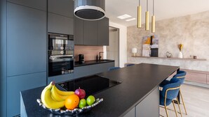 Eine moderne Küche mit Kochinsel, integriertem Backofen und Kaffeemaschine.