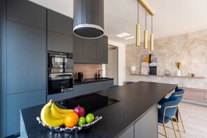 A modern kitchen with a central island, a built-in oven, and a coffee machine. - Stylish 2BDR Apartment with Free Parking & Terrace by EasyBNB Premium (Prague)