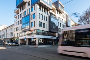 A multi-story building with a Starbucks Coffee on the ground floor, a tram in motion, and a pedestrian crossing. - Stylish 2BDR Apartment with Free Parking & Terrace by EasyBNB Premium (Prague)