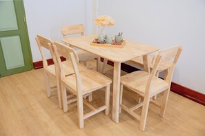 Ein Holzespeisesaal mit vier Stühlen, einer Schale mit Speisen und Getränken und einer Vase mit Blumen.
